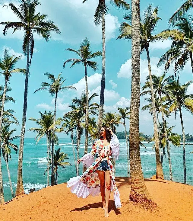 Traveler walking along a tropical beach lined with palm trees in Sri Lanka